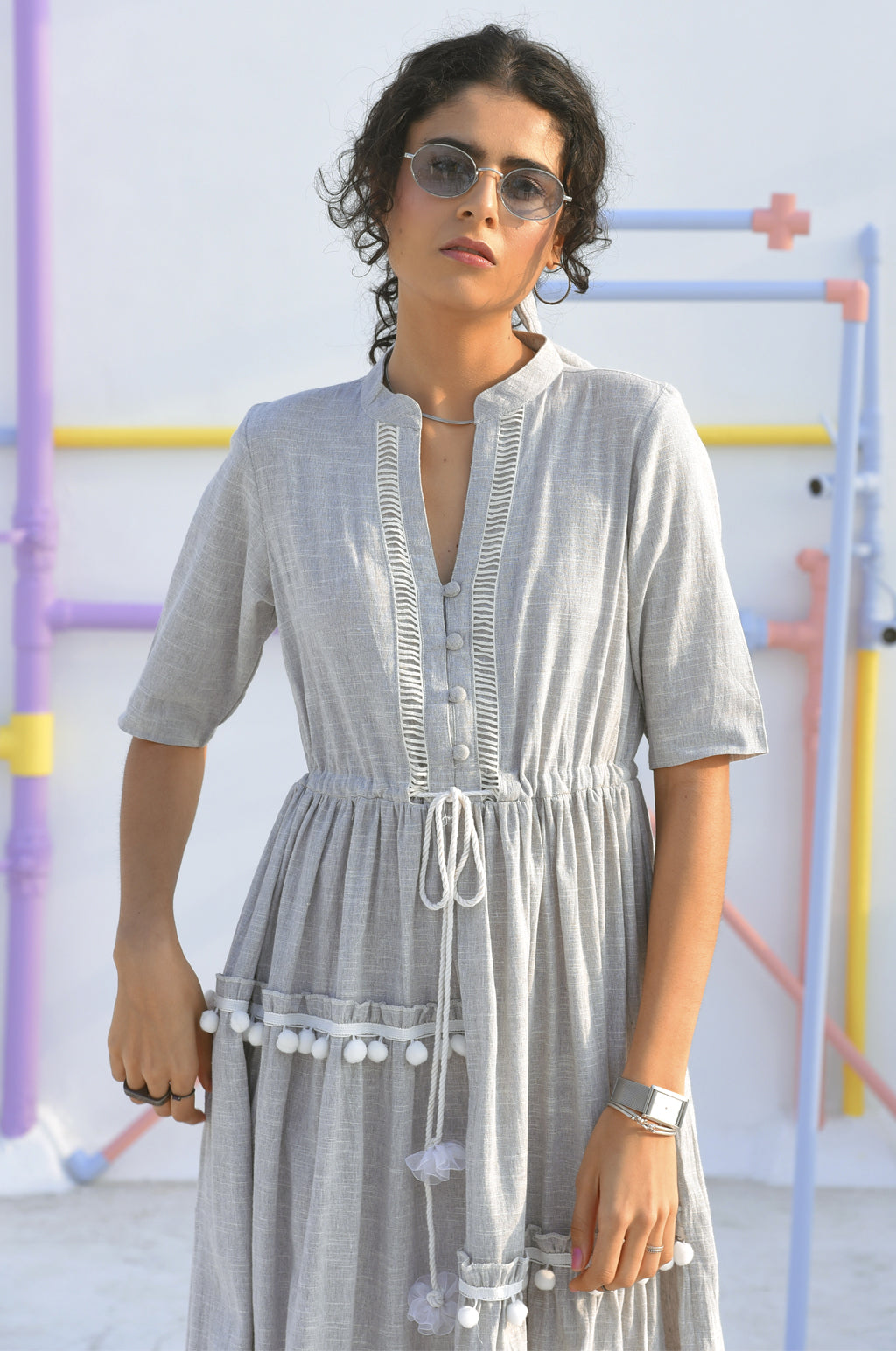 Woman in a grey dress, holding a tote bag.